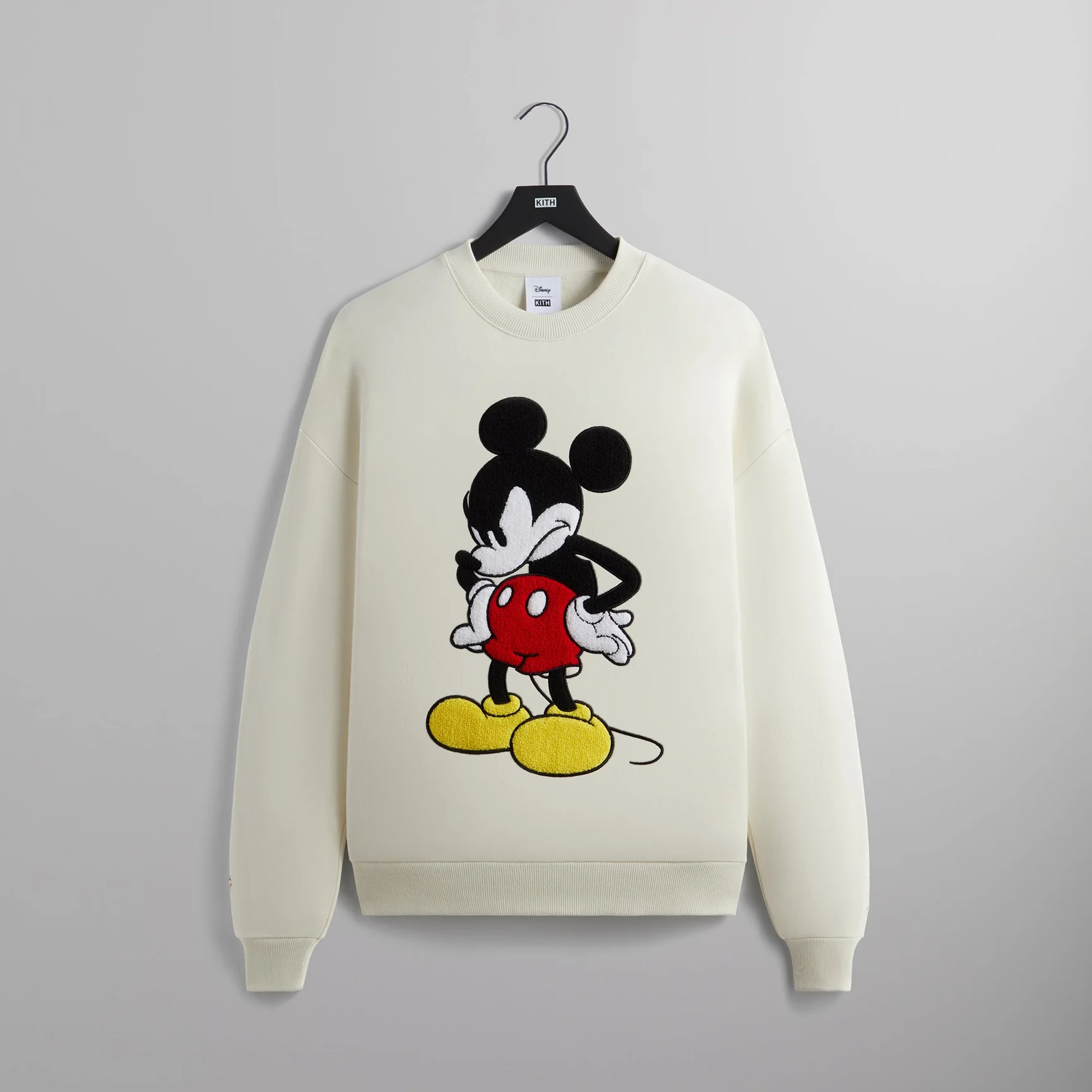 Cream-colored sweatshirt with animated character graphic design on hanger