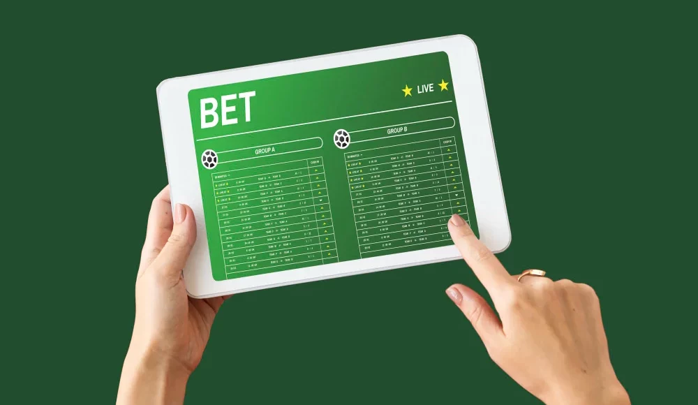 Person holding a tablet showing live soccer betting odds