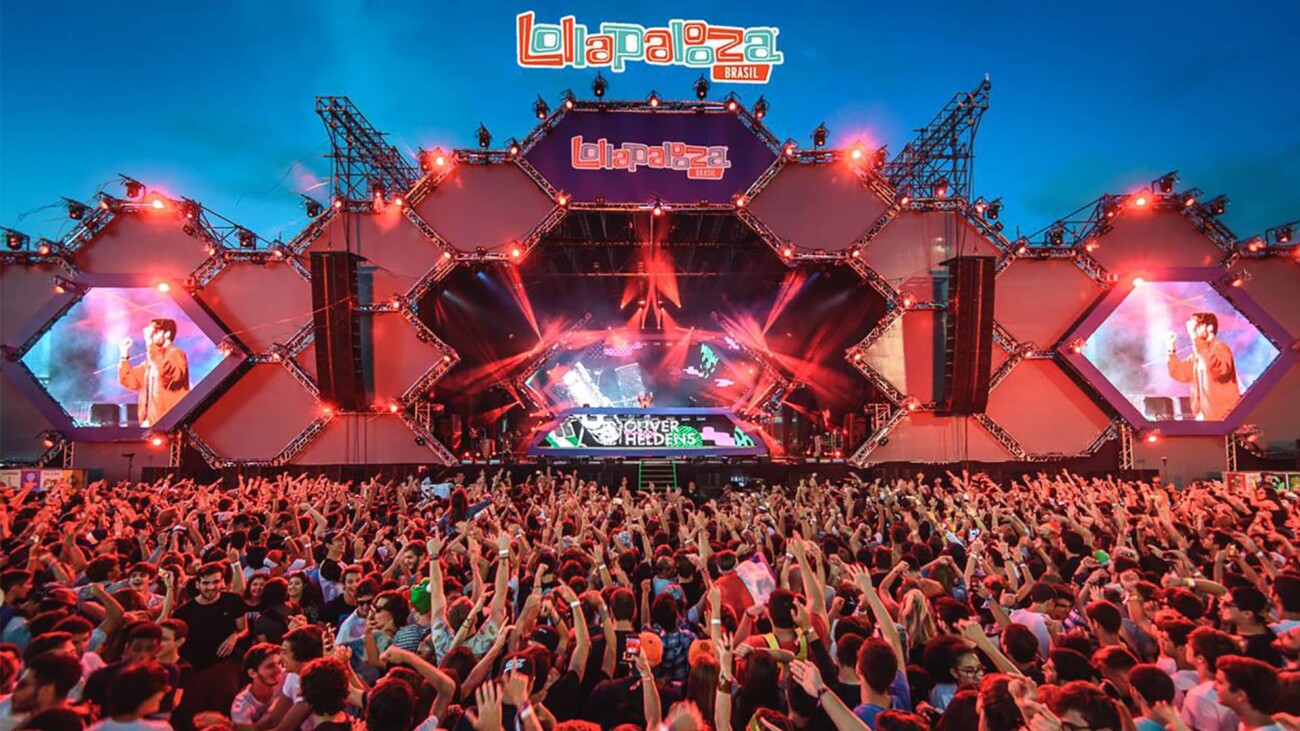 Lollapalooza Brasil music festival crowd with stage lights and live performance displayed on large screens.
