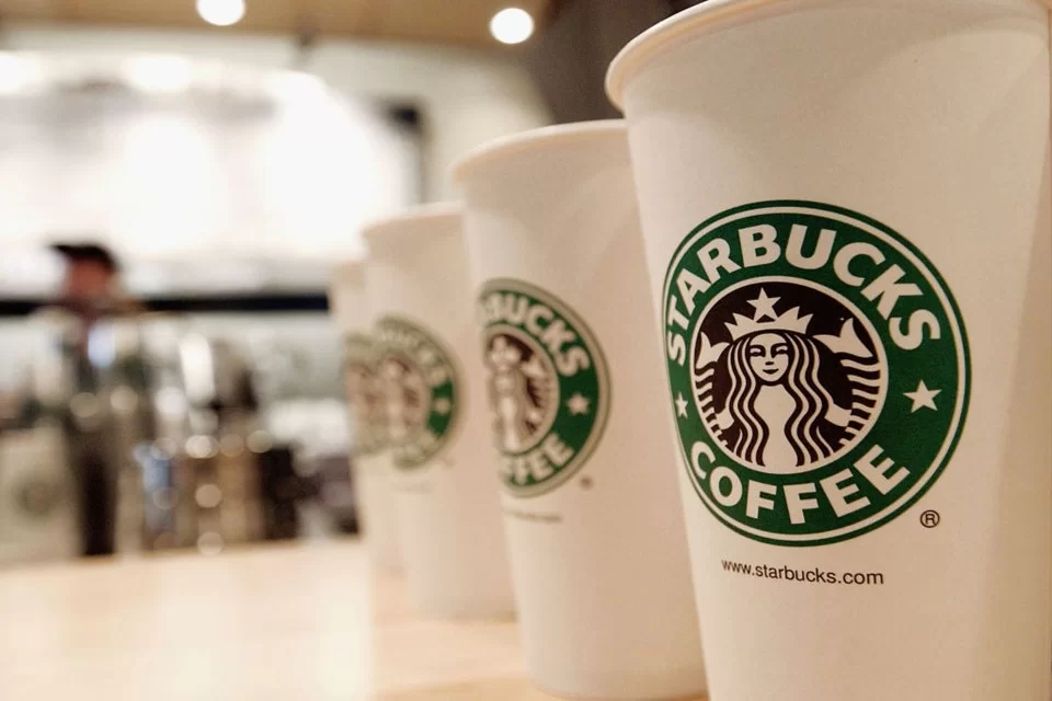 Starbucks coffee cups in focus with blurred barista background in cafe