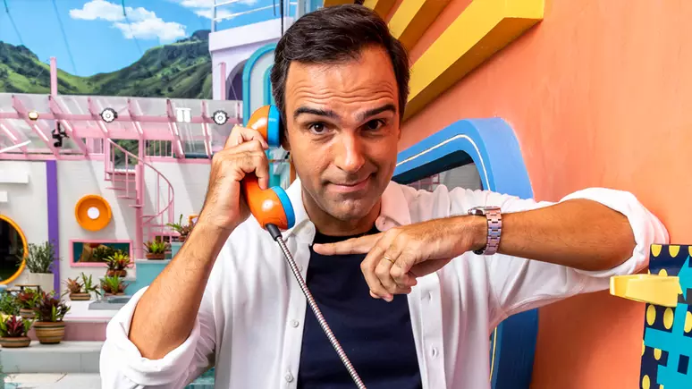 Man holding orange telephone with playful expression in colorful cartoon-like office setting.