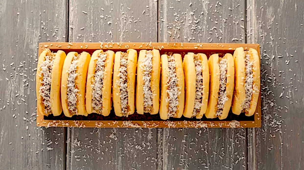 Freshly sliced bananas topped with shredded coconut on a wooden tray over a grey rustic background.