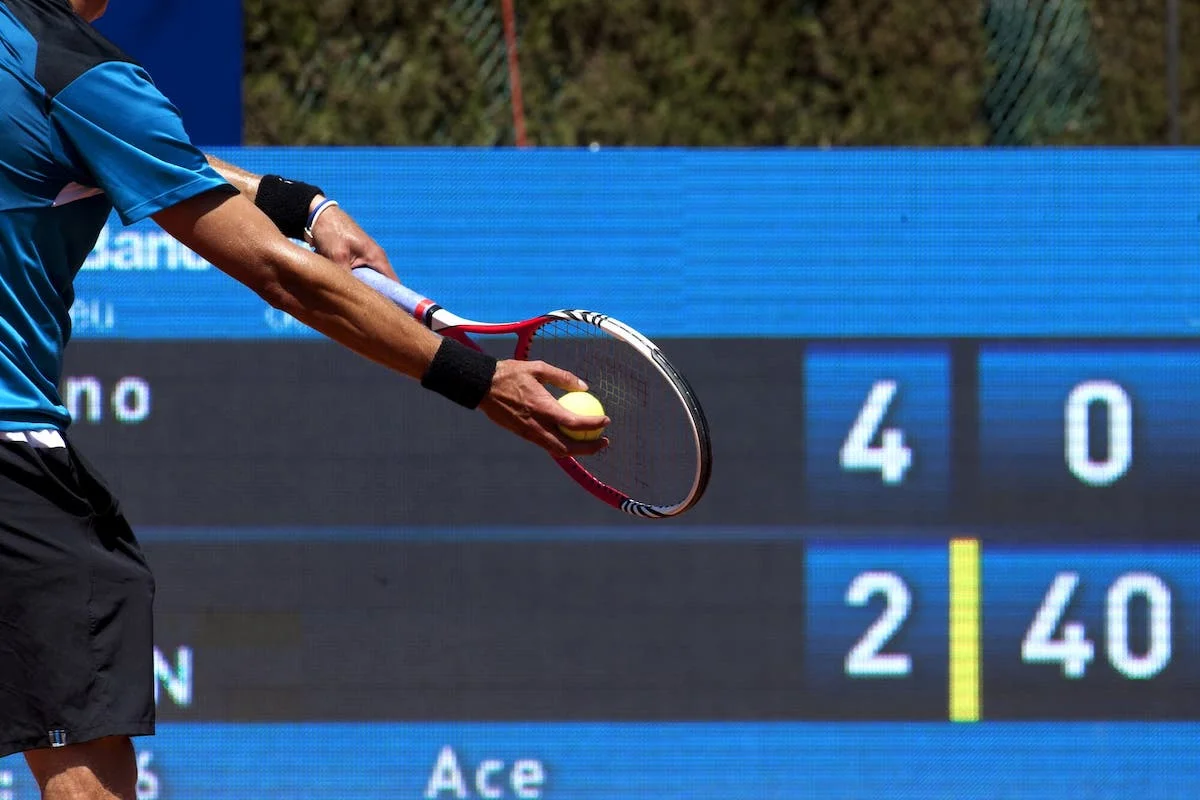 pontuação do tênis. Tennis player preparing to serve with scoreboard in the background showing a match in progress