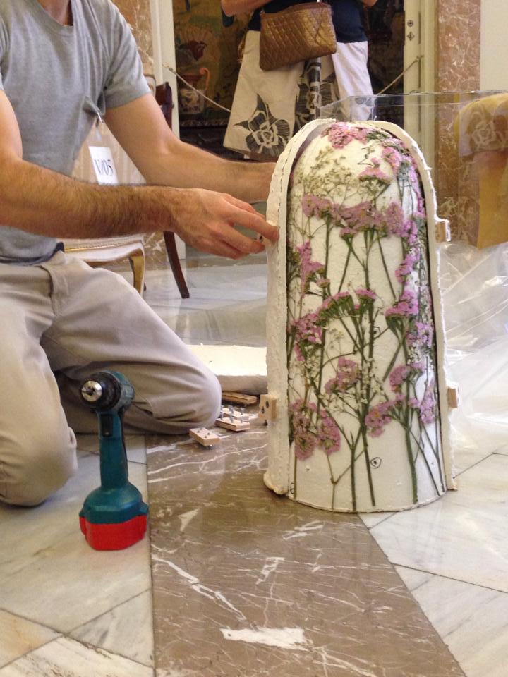 Craftsman restoring floral patterned ceramic art with tools on marble floor.