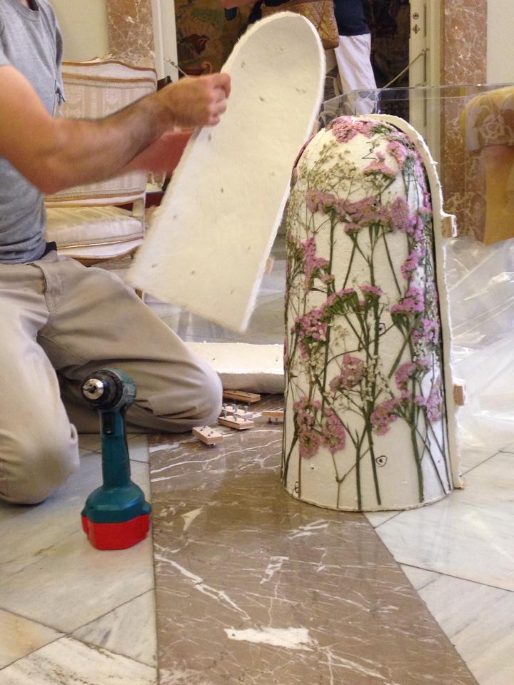 Craftsman upholstering a chair with floral fabric, work in progress with upholstery tools on marble floor.