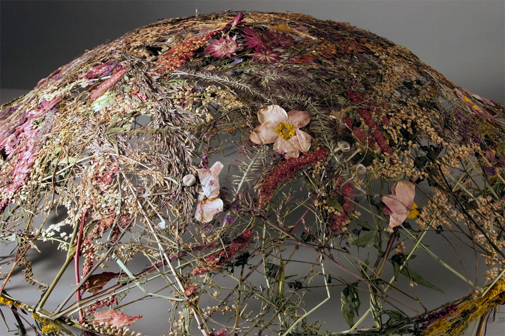 Floral art installation with dried flowers and branches on wireframe dome