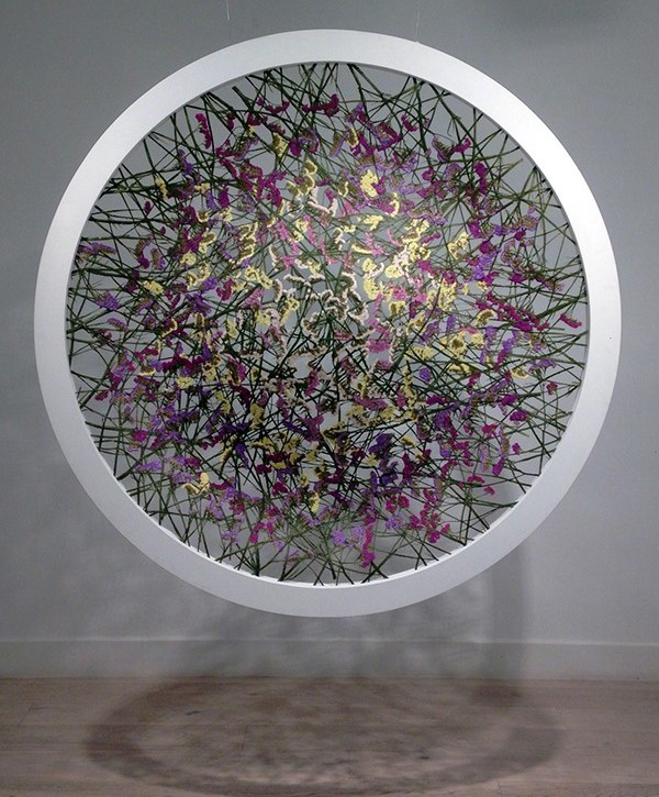 Contemporary abstract art installation featuring colorful tangled lines within a circular white frame displayed in a gallery setting.