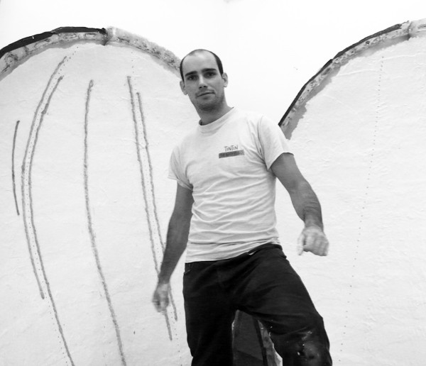 Man posing in front of abstract wall art in black and white photo