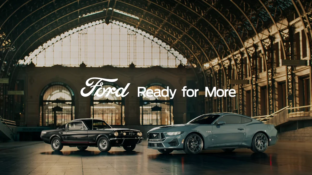 Ford vintage and modern Mustang models showcased in a grand hall with "Ready for More" slogan visible