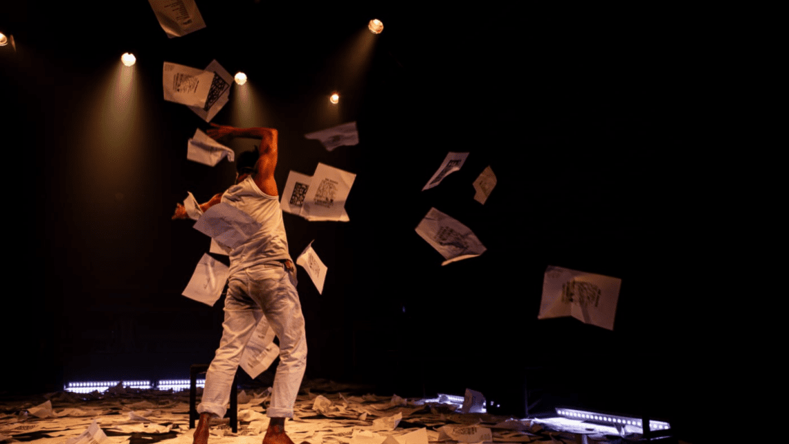 Person throwing papers on stage with dramatic lighting in a theater performance