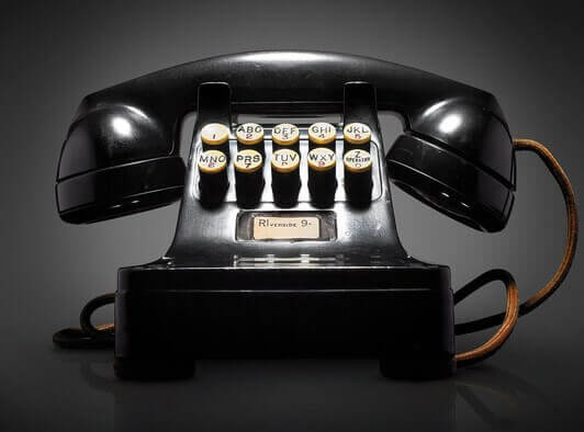 Vintage black rotary dial telephone on dark background