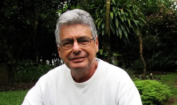 Senior man with glasses smiling in a garden wearing a white t-shirt