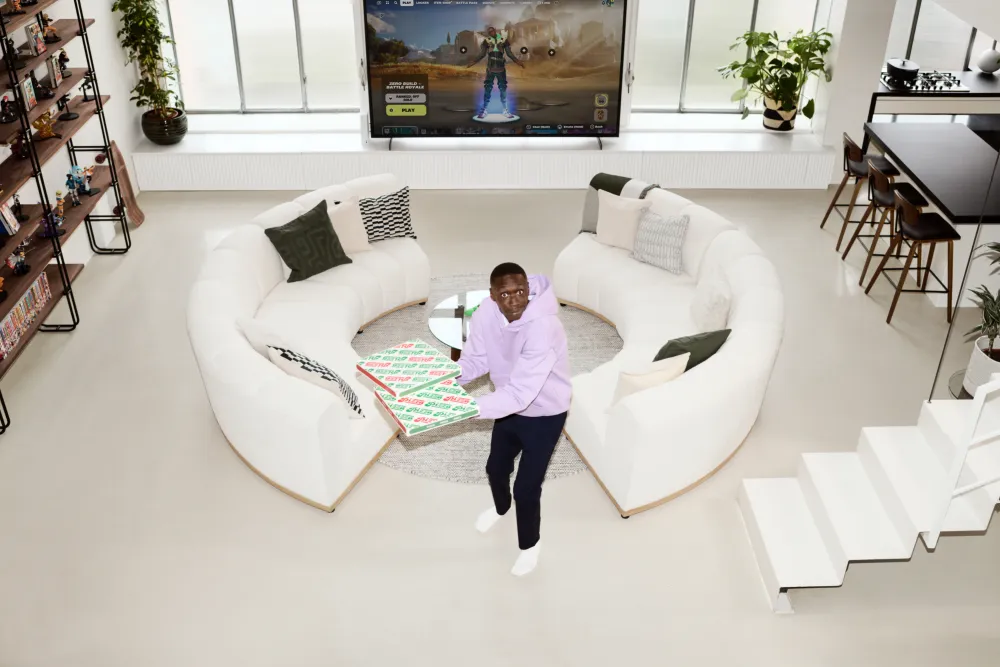 Modern living room interior with curved sofa, large screen TV, and man standing in the middle of the room
