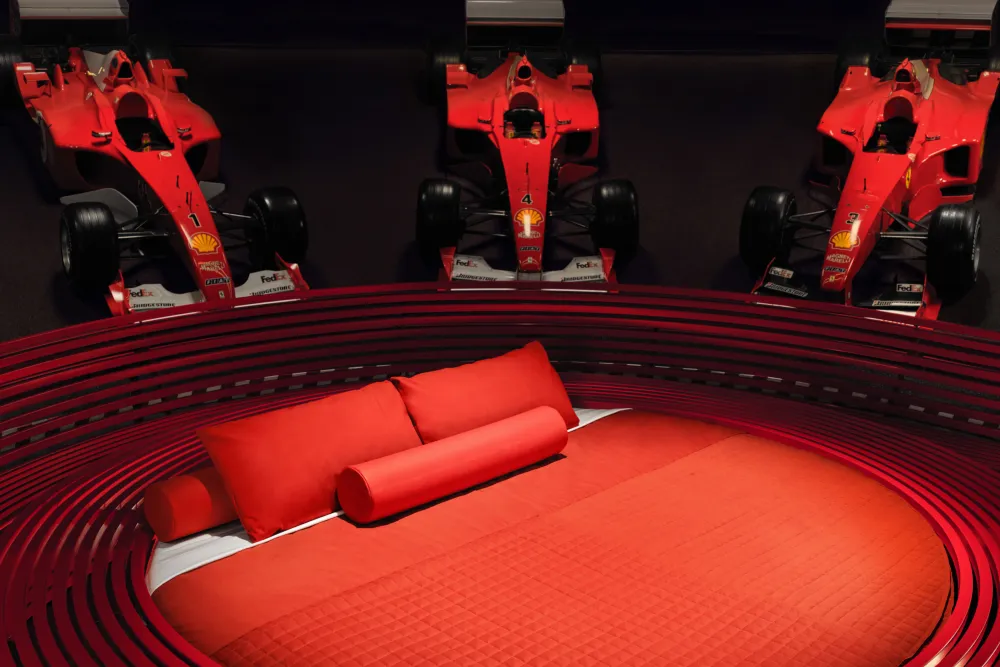 Luxury home theater with red sofa and Formula 1 racing car models on display.