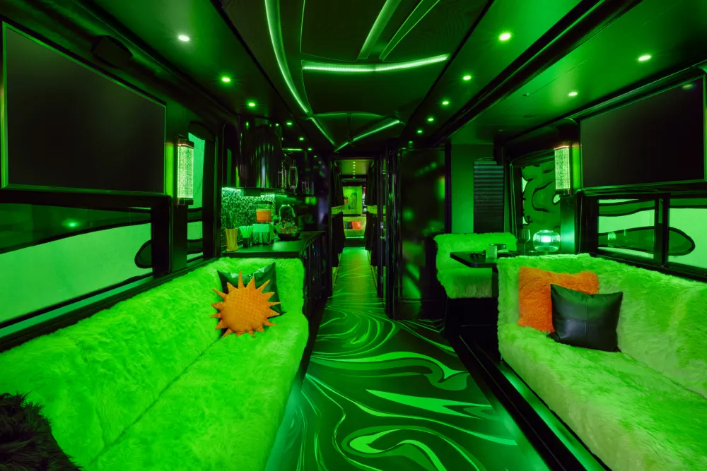 Luxury party bus interior with neon green lighting, plush seating, and modern amenities.