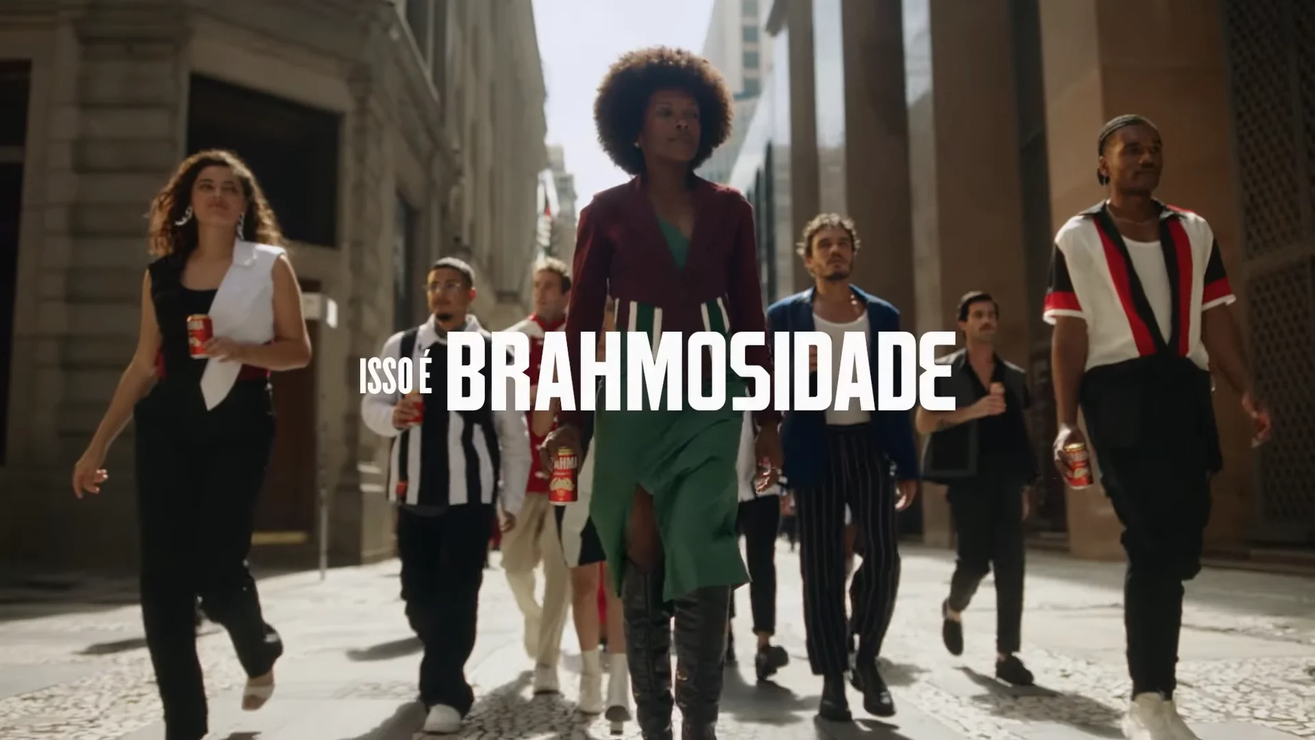 Diverse group of stylish people walking confidently in urban setting with text 'ISSO É BRAHOSIDADE' and holding cans of Brahma beer.