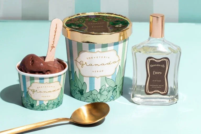 Sorveteria Granado ice cream cup and container with spoon next to Granado perfume bottle on teal striped background.