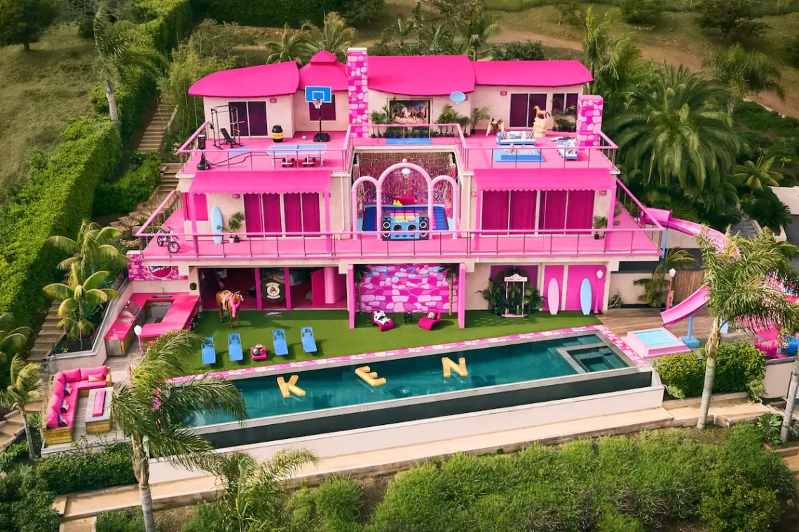 Pink-themed luxury villa with pool and waterslide, surrounded by tropical greenery.