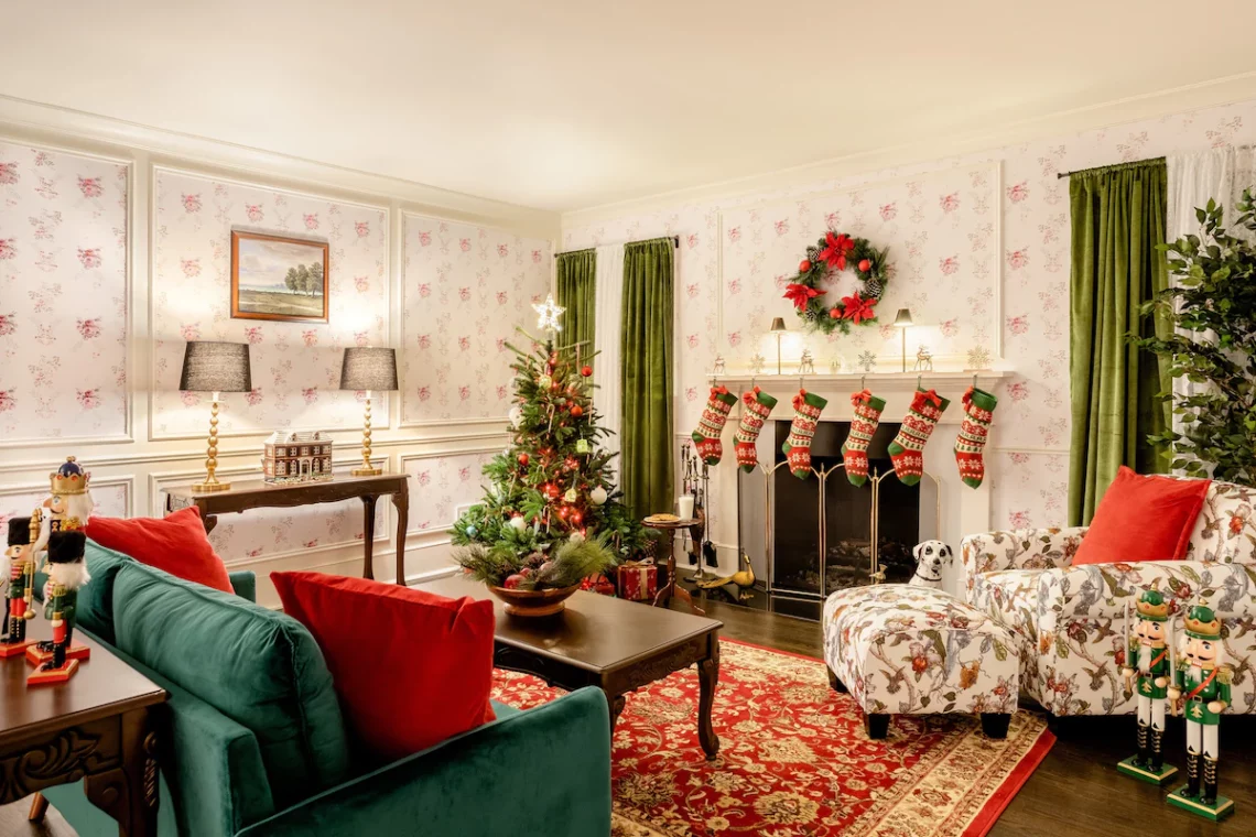 Elegant living room decorated for Christmas with stockings hanging on fireplace, tree with ornaments, and festive wreath.