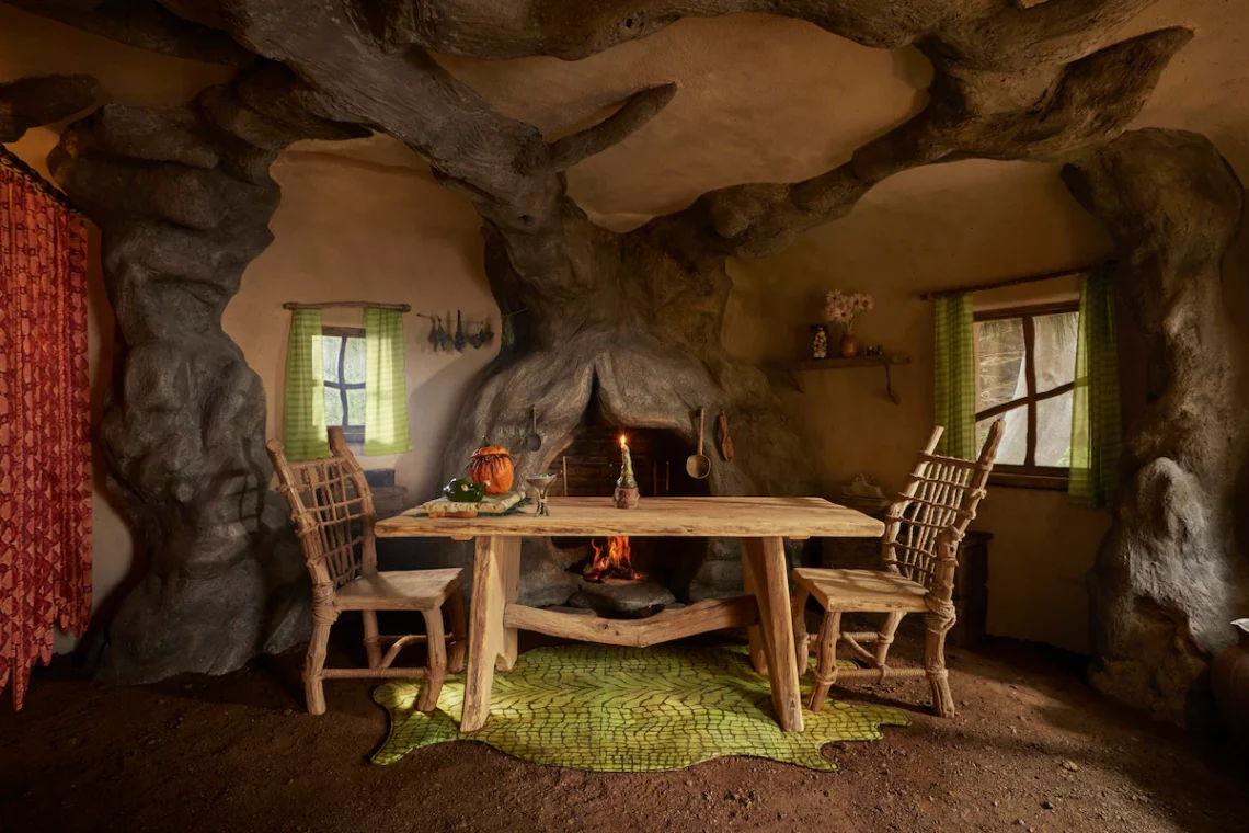 Rustic treehouse interior with wooden furniture, carved tree branches, and fireplace